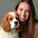 Jessica smiling next to her freshly groomed Cocker Spaniel Oscar